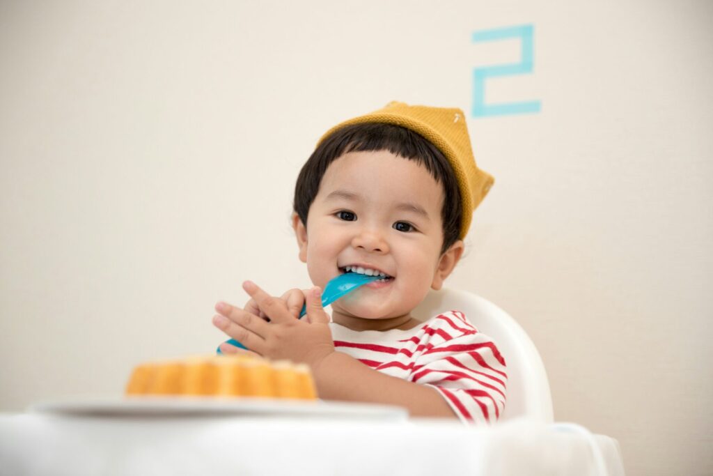 食卓でスプーンをくわえる幼児