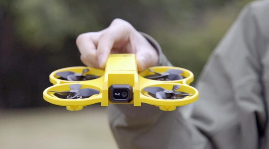 片手でつままれる黄色い小型ドローン