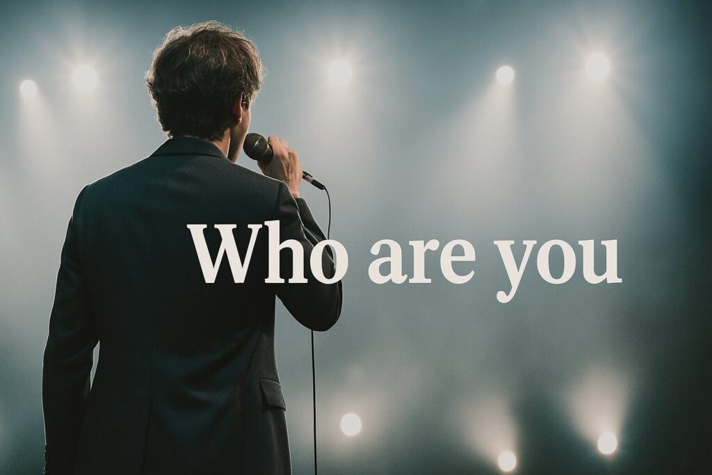 ライトが眩しいステージで歌う歌手の後ろ姿
白い「Who are you」のタイトル