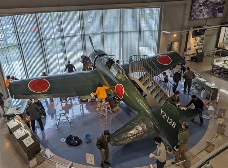 展示中のレシプロ戦闘機を清掃するボランティア団体