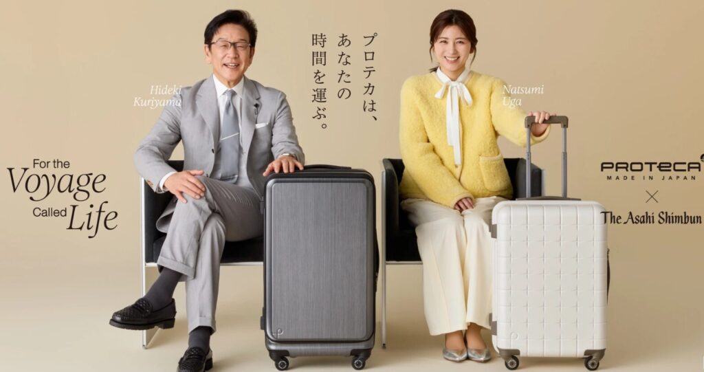 椅子に座り、スーツケースに手を置いてほほ笑む男女の旅行客。スーツケース・バッグの販促宣材写真
